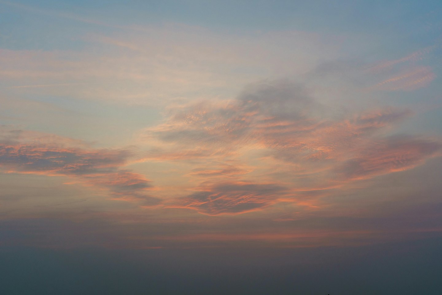 淡いパステルカラーの雲が、オレンジとピンクの夕焼け空に浮かんでいる。